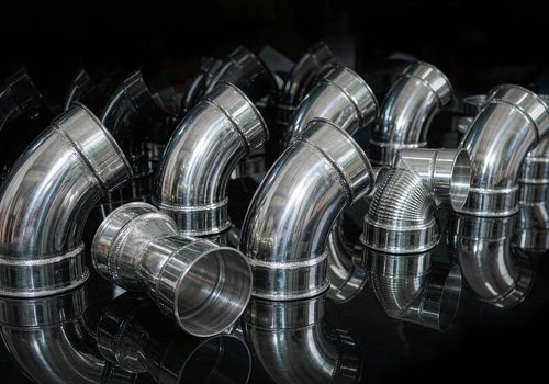 Gleaming stainless steel pipe fittings and elbows in rows